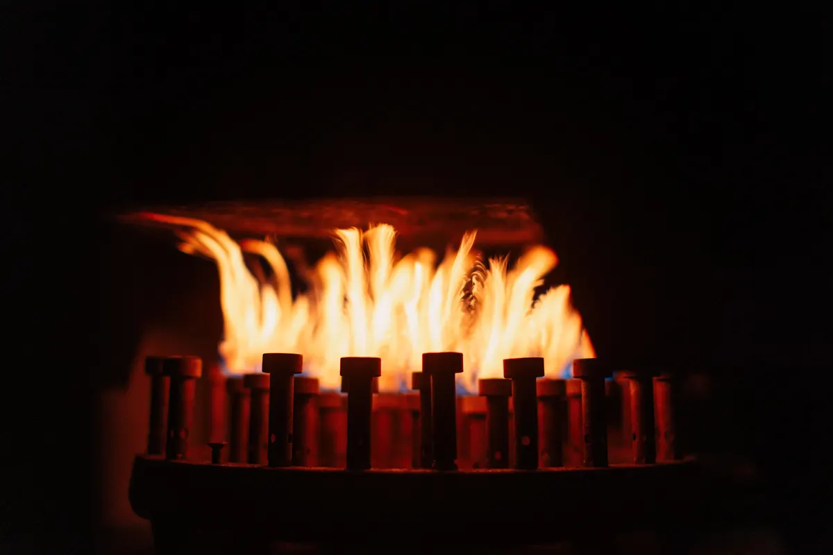 Close up of blue and orange natural gas flames burning across a row of burner nozzles, the same fuel a natural gas standby generator draws on