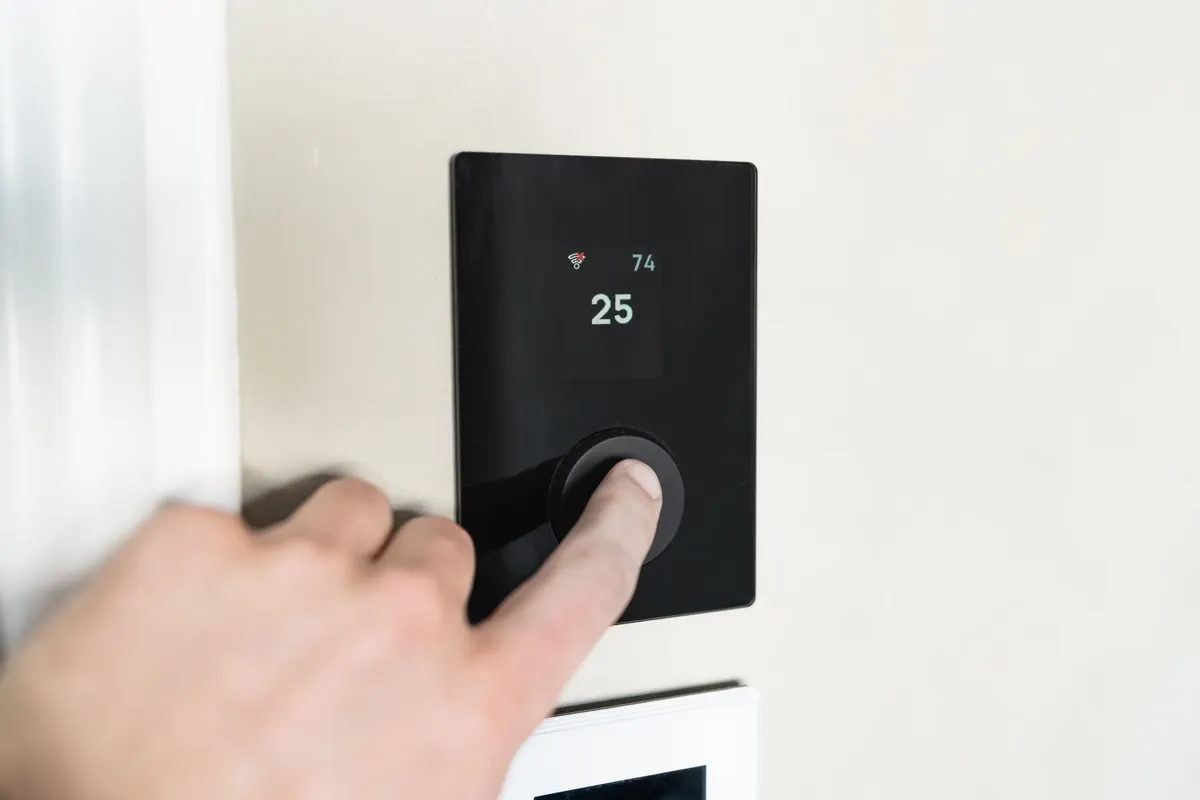 Hand adjusting a smart thermostat during a cold snap, checking the indoor temperature