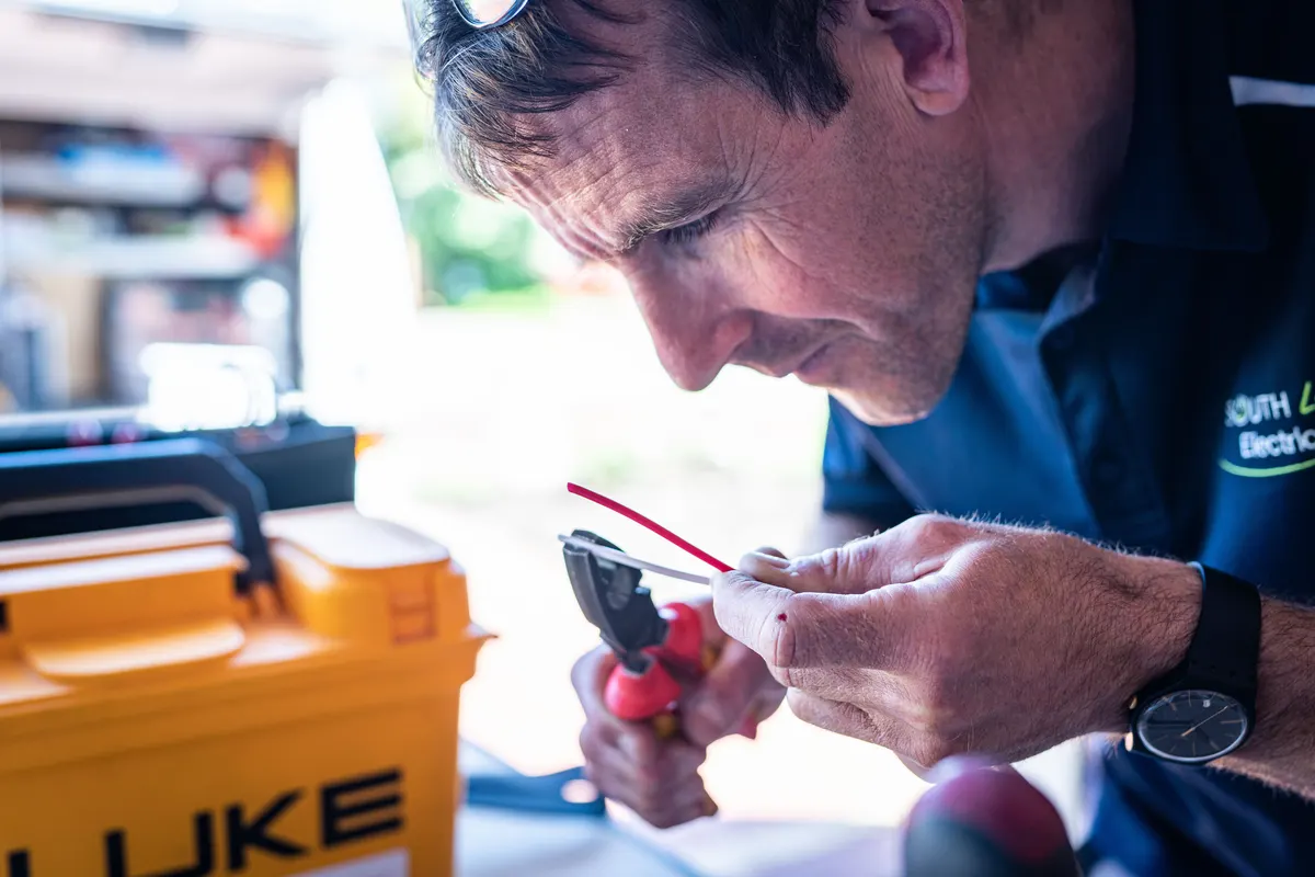 Electrician stripping wire during a residential generator electrical hookup