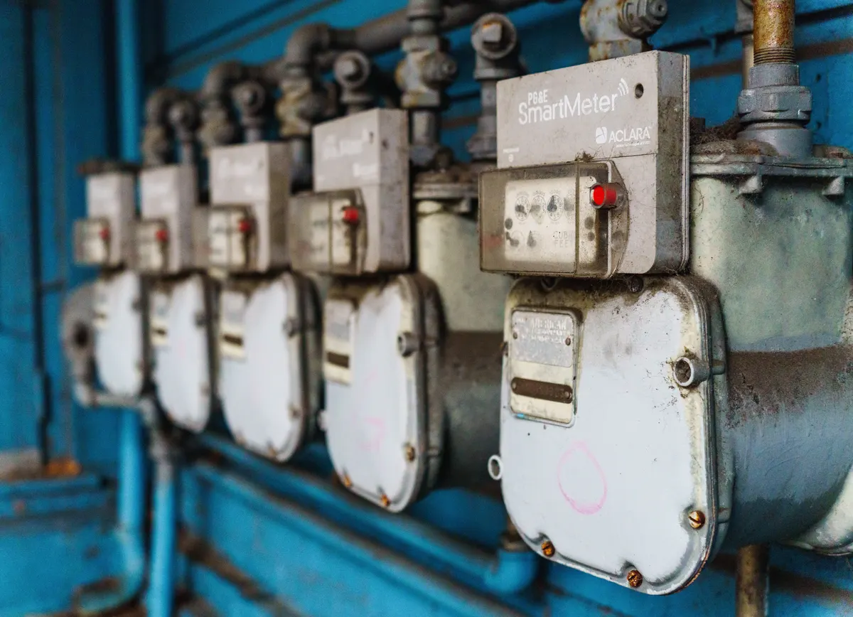 Row of natural gas meters mounted on an exterior wall, the kind of utility connection a natural gas standby generator relies on