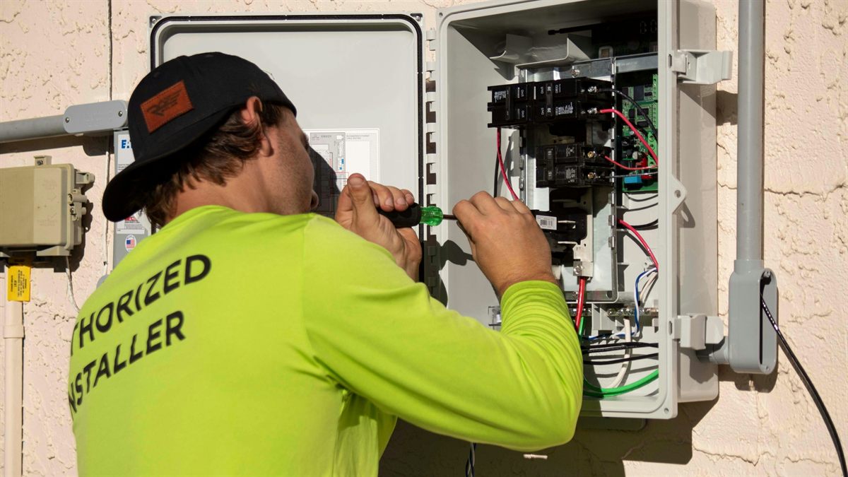 Electrician in a hard hat holding equipment near residential electrical service
