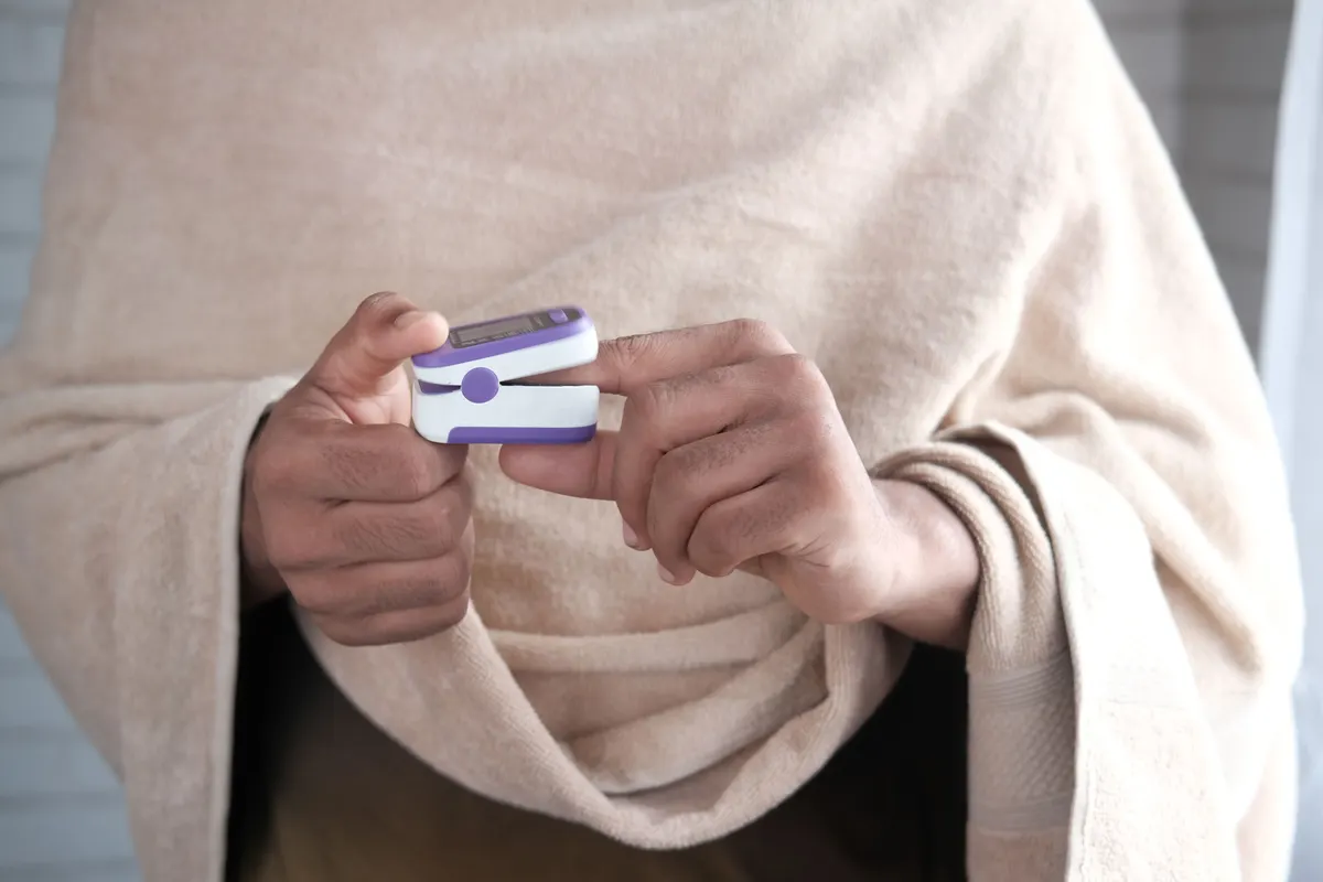 Person at home checking a pulse oximeter to monitor oxygen levels during a power outage