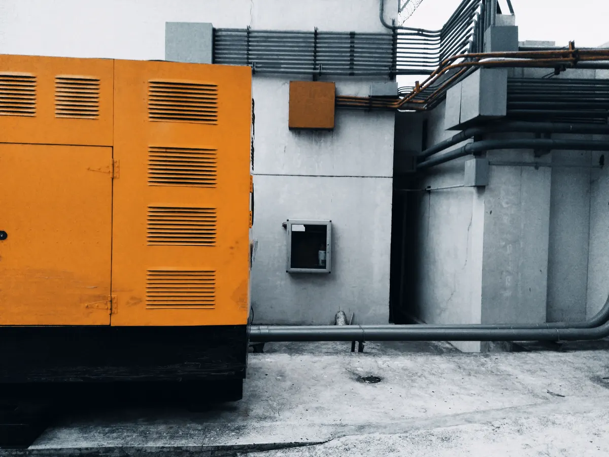 Standby generator enclosure outdoors with visible gas piping and control wiring